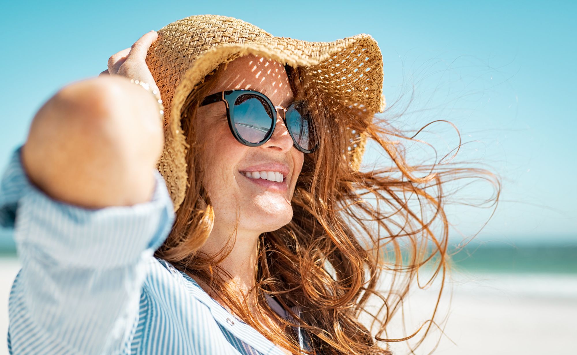Mujer en la playa con gafas y sombrero